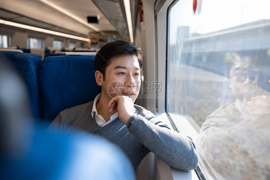 坐在火车上的男性看着窗外风景