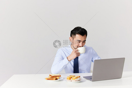 边吃早饭边工作的男性图片