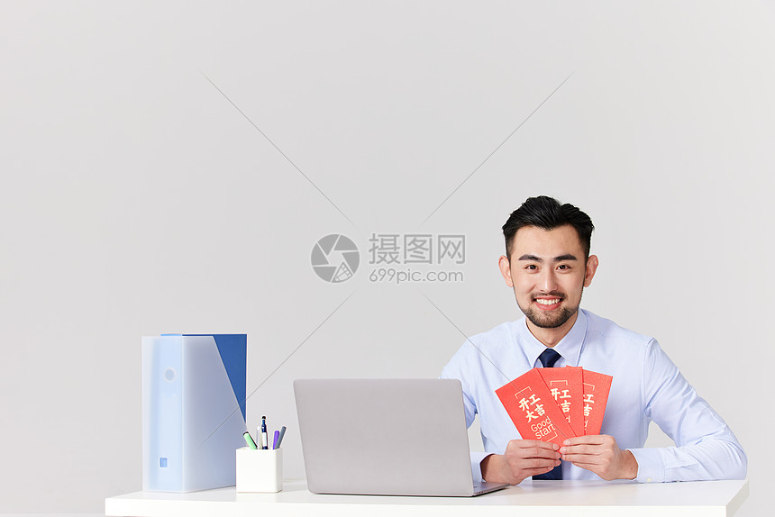男性坐在办工作拿着开工大吉的红包图片