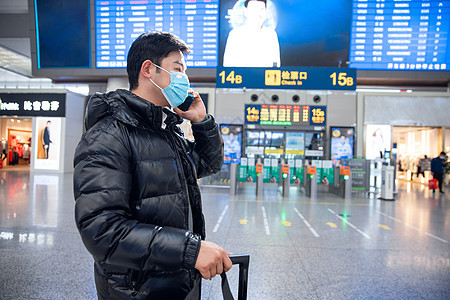 春节回家戴着口罩站在入站口打电话的男性图片