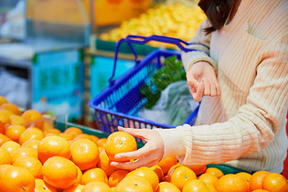 年轻女性超市挑选购买橙子图片