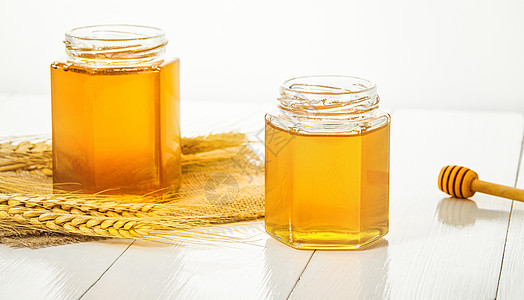 白色桌面上的蜂蜜罐子图片