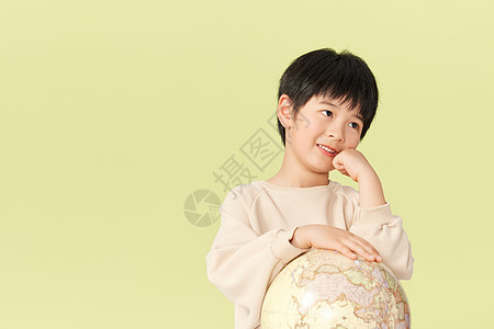 抱着地球仪思考的小男孩图片