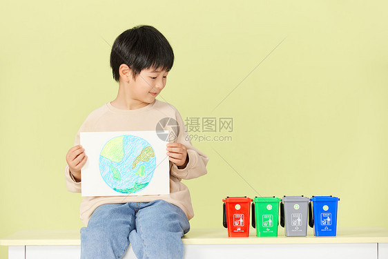 小男孩抱着手绘地球画看着垃圾分类桶图片