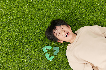 在草坪上的一家人图片躺在草坪上的小男孩旁边放着可回收符号背景