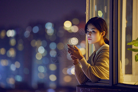 深夜阳台玩手机的年轻女性高清图片