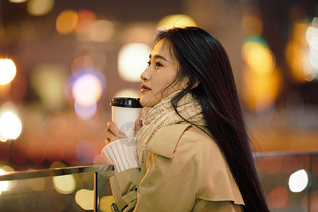 冬季夜晚都市女性手握咖啡杯侧脸图片