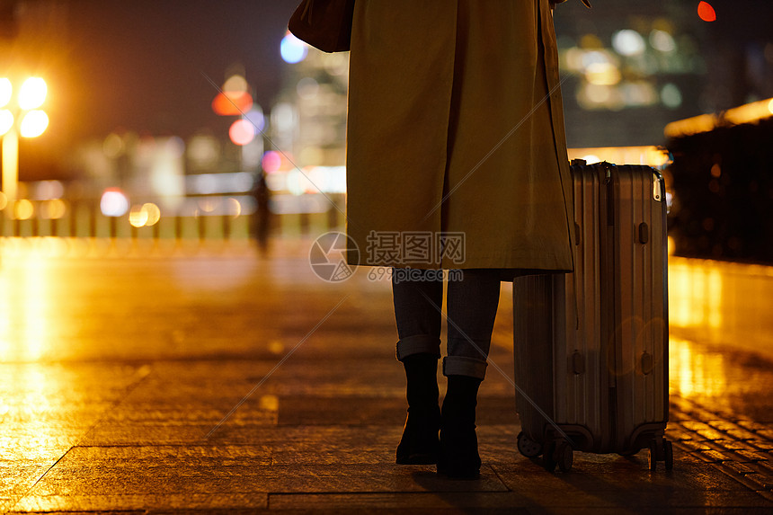 夜晚都市女性手提行李箱走在路上