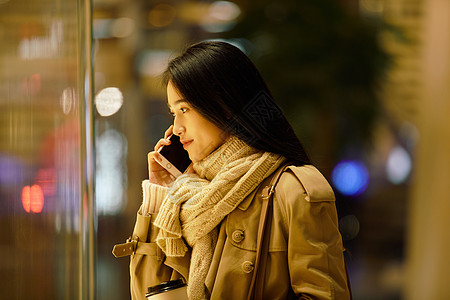 都市女性夜晚手握咖啡杯打电话图片