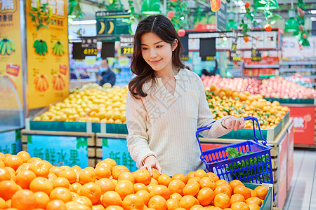 超市购物挑选橘子的青春女性图片