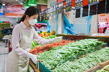 佩戴口罩的超市服务员整理蔬菜区图片