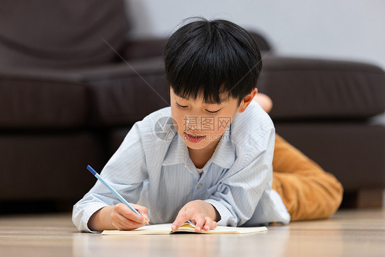 小男孩趴在地上做作业图片