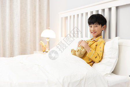 抱玩具熊男孩小男孩抱着玩偶熊躺在床上背景