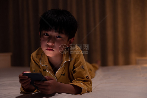 在黑夜里拿着手机表情难过的小男孩图片