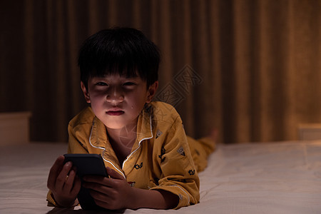 在黑夜里拿着手机表情难过的小男孩图片