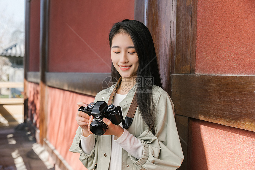 美女大学生一个人旅行拍照看相机图片