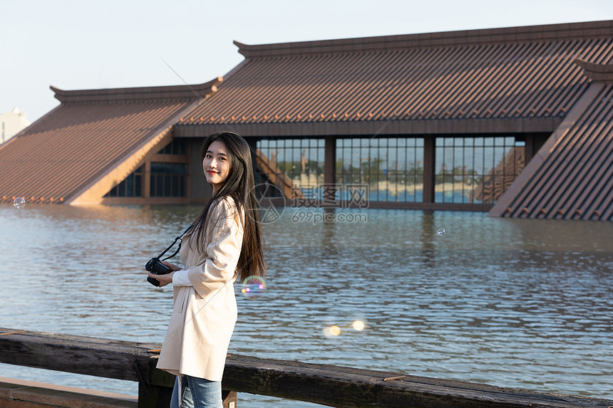 青春美女大学生背着相机旅行拍照图片