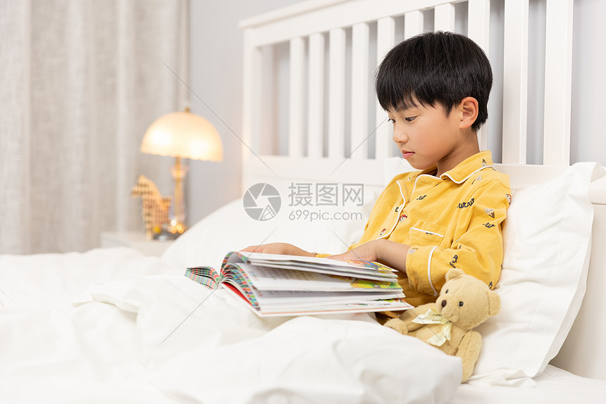 小男孩睡前在床上看书图片