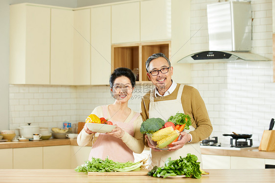 厨房里中老年夫妇手捧新鲜蔬菜图片