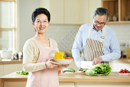 中老年女性手捧新鲜蔬菜背景