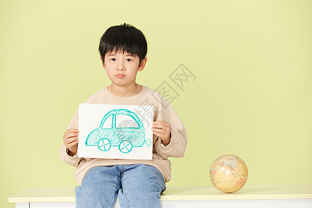 小男孩拿着手绘的汽车图片