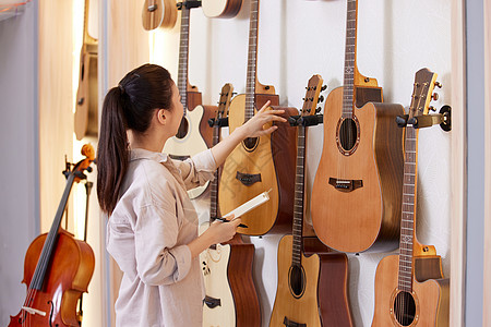 商店老板琴行老板清点墙上的吉他数量背景