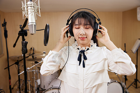 录音棚内唱歌的女性戴耳机图片