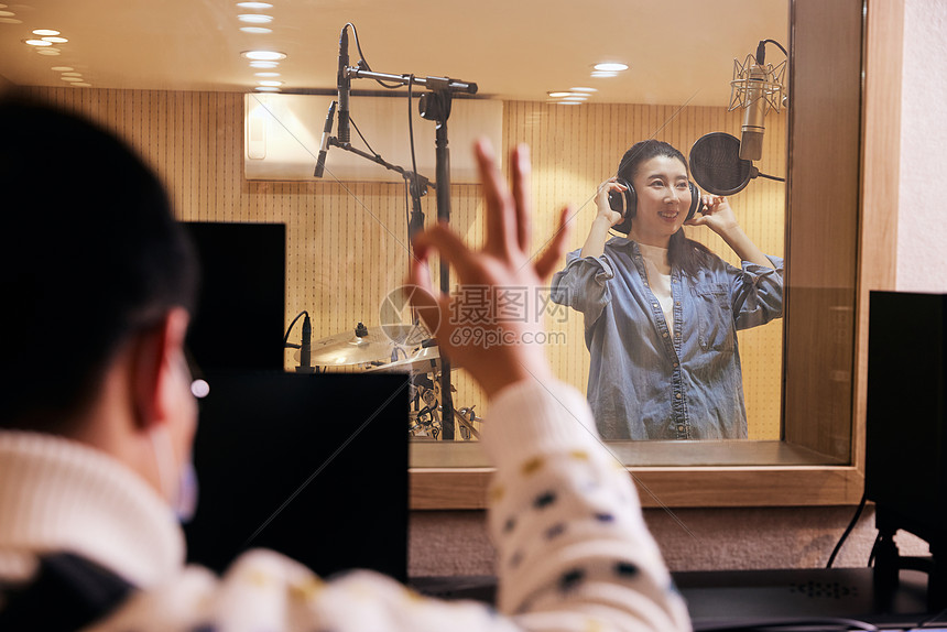 录音棚内唱歌的女性录音棚外的人对棚内的人比ok手势