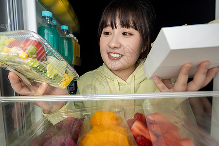 打开盒子女性晚上打开冰箱拿取食物背景