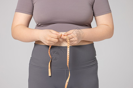 女性用皮尺测量腰围特写背景图片
