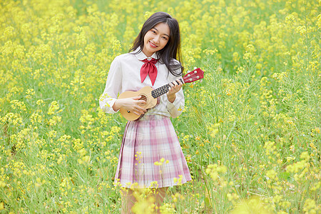 油菜花花海中的少女弹吉他背景图片