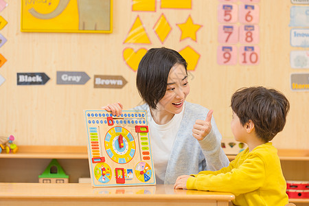 幼儿园学生老师夸赞小男孩玩玩具背景