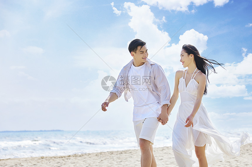 年轻情侣牵手海边散步图片