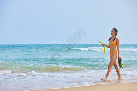 比基尼美女手拿浮潜设备海边行走图片