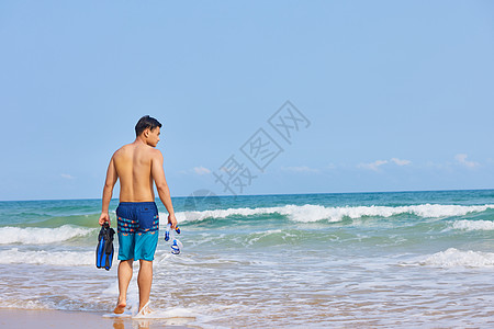 海滩背影青年男性手拿潜水装备背影背景