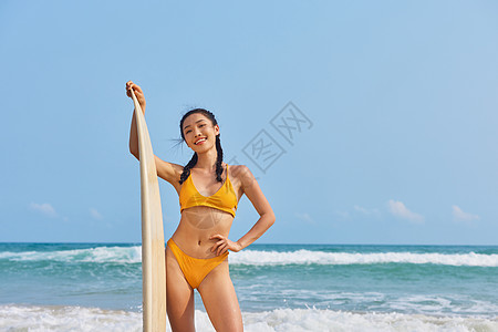 海边美女海边比基尼美女手拿冲浪板背景