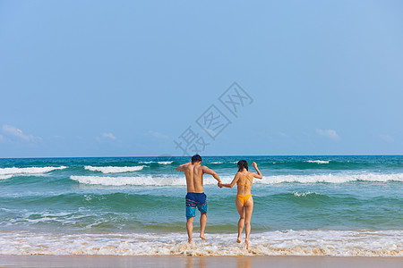年轻情侣牵手奔向大海背影高清图片