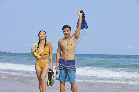 海边情侣青年男女手拿潜水装备背景