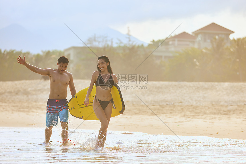 年轻男女手拿冲浪板海边行走图片