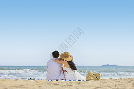 海边美女年轻情侣夏日坐在沙滩看海背影背景