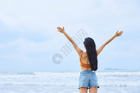 海边嬉戏夏日海边美女张开手臂背影背景