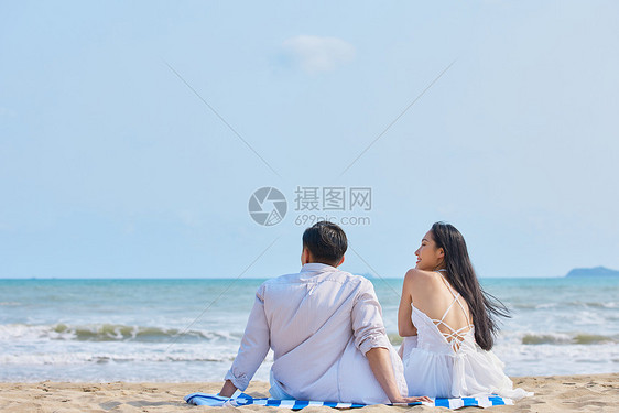 年轻情侣坐在沙滩看海背影图片