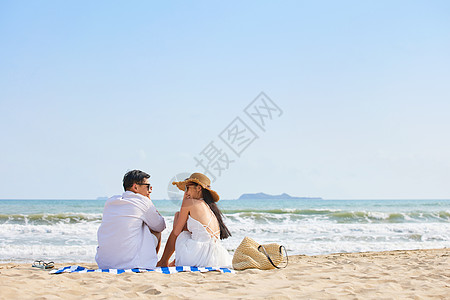 年轻情侣坐在沙滩看海背影高清图片