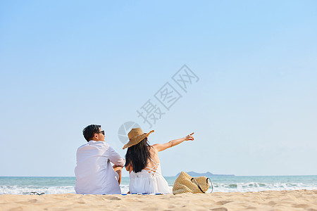 浪漫情侣夫妻度假旅行年轻情侣坐在沙滩看海背影背景