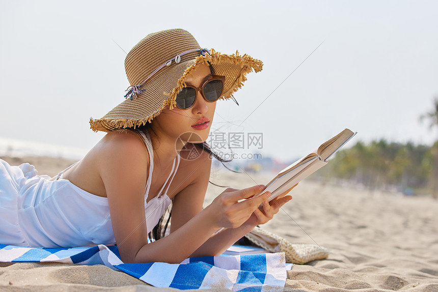 年轻美女海边度假看书图片