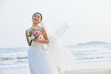 海边婚纱美女手拿手捧花图片