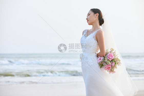 海边婚纱美女手拿手捧花图片