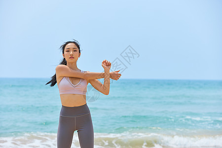 年轻美女海边运动拉伸图片