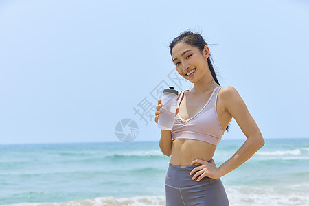 年轻美女海边运动休息喝水图片