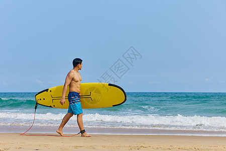 年轻男士拿着冲浪板海边行走高清图片